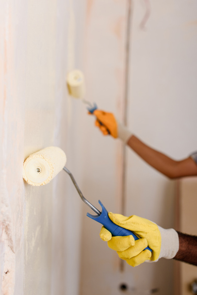 cropped image of couple painting wall by paint rollers at new home - Foto, imagen