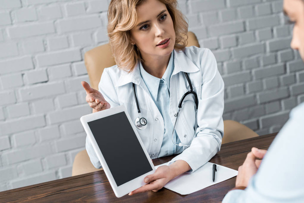 medico di sesso femminile che mostra tablet con schermo bianco al paziente in ufficio
 - Foto, immagini
