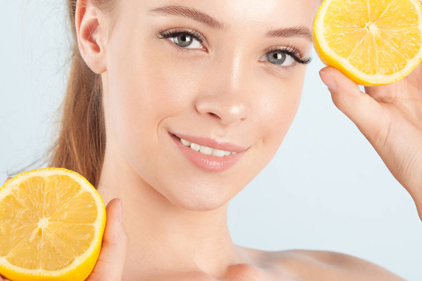 Young beautiful girl with clean perfect skin with lemon close-up. Cosmetics and care for young skin - Фото, зображення