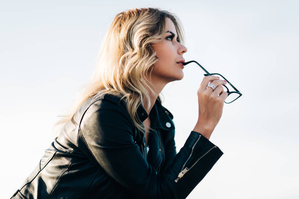 Side portrait of young blonde with glasses in hands - Foto, imagen