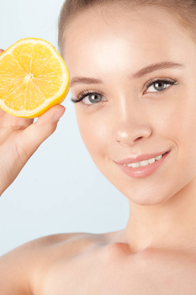 Young beautiful girl with clean perfect skin with lemon close-up. Cosmetics and care for young skin - Zdjęcie, obraz