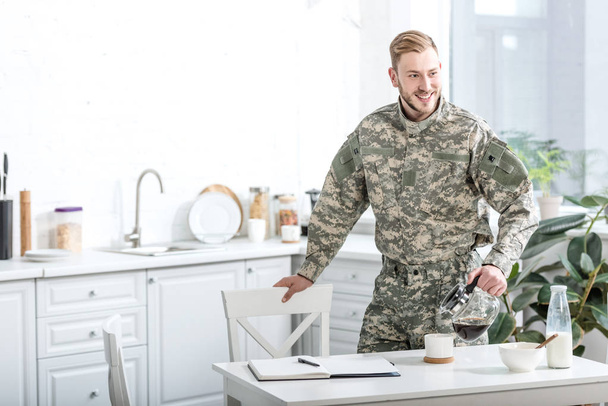 χαμογελώντας στρατού στρατιώτης ρίχνει καφέ στην κουζίνα - Φωτογραφία, εικόνα
