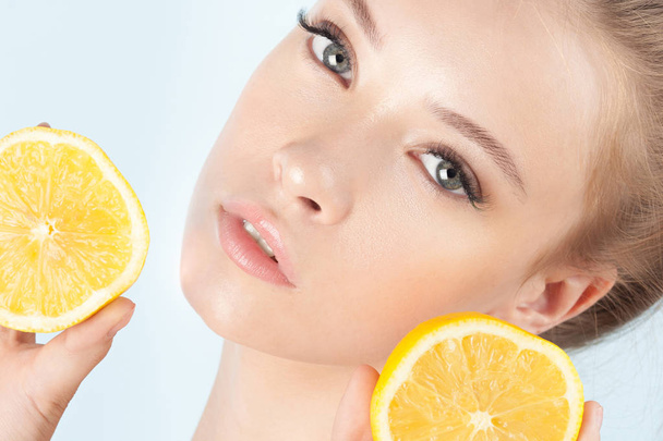 Young beautiful girl with clean perfect skin with lemon close-up. Cosmetics and care for young skin - Fotó, kép