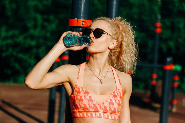 Photo of sports woman wearing sunglasses with bottle of water ne - Foto, Imagem