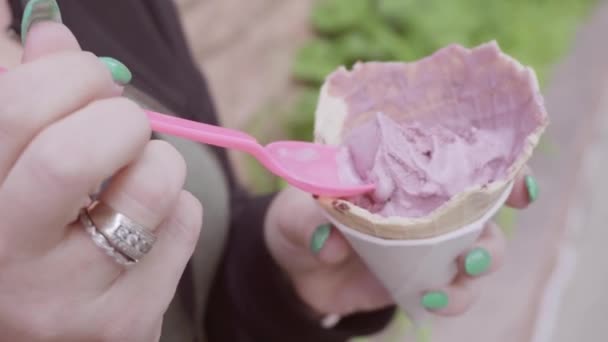 Woman with blue nails eating ice cream outside. - Video