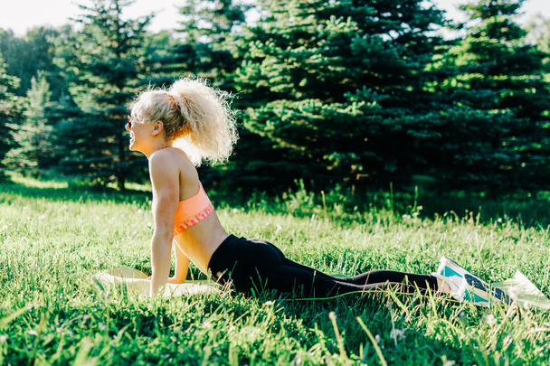 Foto de una joven deportista de pelo rizado practicando yoga sobre una alfombra
  - Foto, Imagen