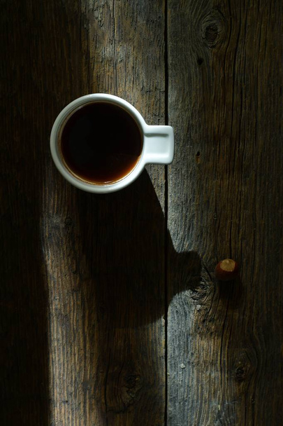Kop koffie en zonlicht op de houten tafel achtergrond  - Foto, afbeelding