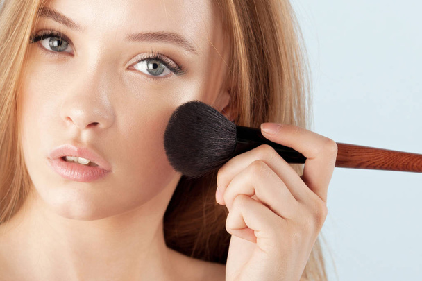 Young beautiful girl with brush for powder close-up. Cosmetics and care for young skin - Φωτογραφία, εικόνα