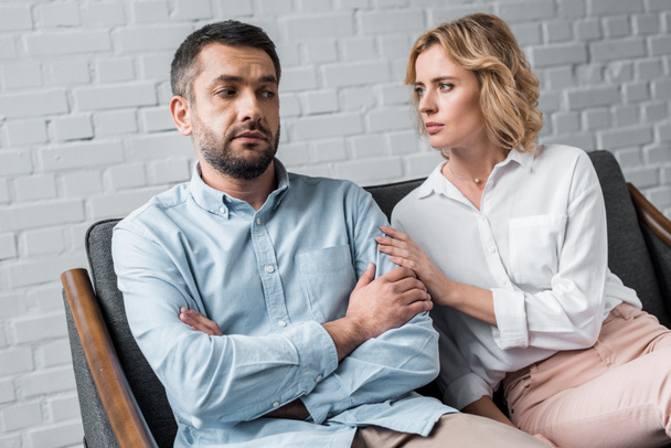 woman talking to depressed husband while sitting on couch after quarrel - Foto, Imagem