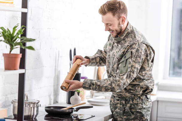 army soldier using pepper pot while cooking in kitchen  - Fotó, kép