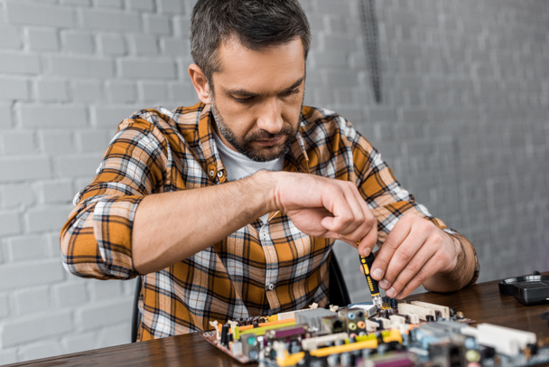 computer engineer repairing motherboard with screwdriver - Fotó, kép