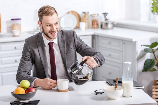handsome businessman pouring filtered coffee in cup at kitchen table - Fotoğraf, Görsel