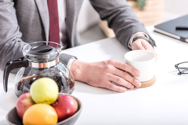 cropped view of businessman drinking coffee in kitchen  - Fotografie, Obrázek