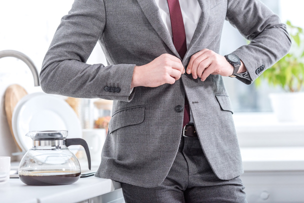 cropped view of businessman fixing button on suit  - Photo, image