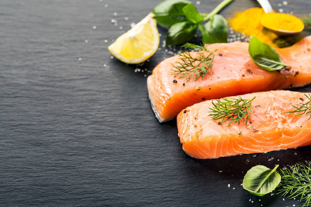 Raw fresh tasty salmon steaks on black table with ingredients - Photo, image