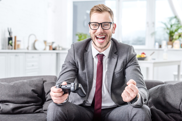 excited businessman holding console and playing video game at home - Foto, Imagen