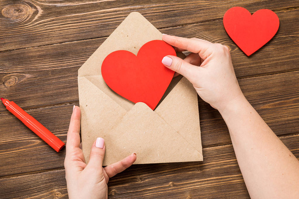 Felülnézet. Kezét a lány szerelmes levél írása a Szent Valentin-nap. Kézi készítésű képeslapot piros szív alakú ábrát. Február 14-én ünnep ünnepe. Valentin nap fogalom-val másol hely. - Fotó, kép