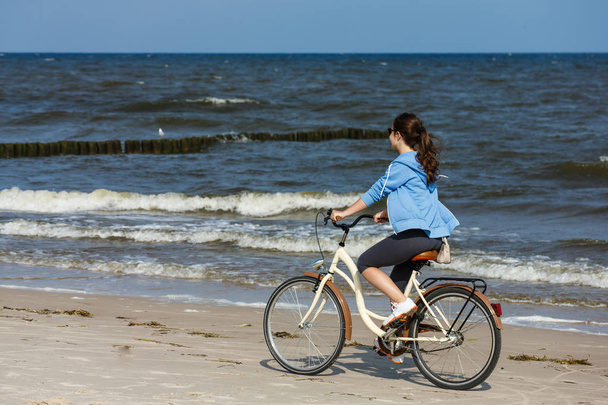 Teenager girl riding bicycle at seaside. Sport and leisure concept. - Foto, Bild