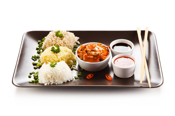 Variety of rice piles with stewed spicy mushrooms, sauces and chopsticks on brown plate - Photo, Image