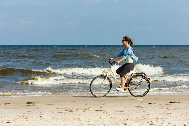 Teenager girl riding bicycle at seaside. Sport and leisure concept. - Photo, Image