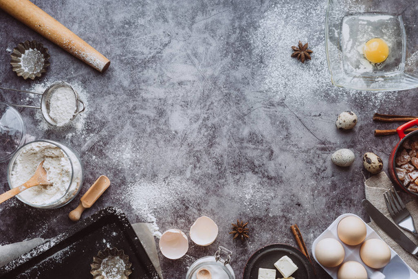 Healthy baking ingredients. Spoon with flour, dishes, eggs, butter salt and rolling pin on a grey background.Bakery background frame. Top view, copy space. - Foto, Imagem