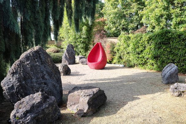 オランダの美しい秋の庭で太陽を楽しむに赤のデザインの椅子 - 写真・画像