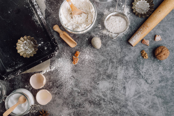 Healthy baking ingredients. Spoon with flour, dishes, eggs, butter salt and rolling pin on a grey background.Bakery background frame. Top view, copy space. - Foto, Bild