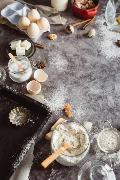 Healthy baking ingredients. Spoon with flour, dishes, eggs, butter salt and rolling pin on a grey background.Bakery background frame. Top view, copy space. - 写真・画像