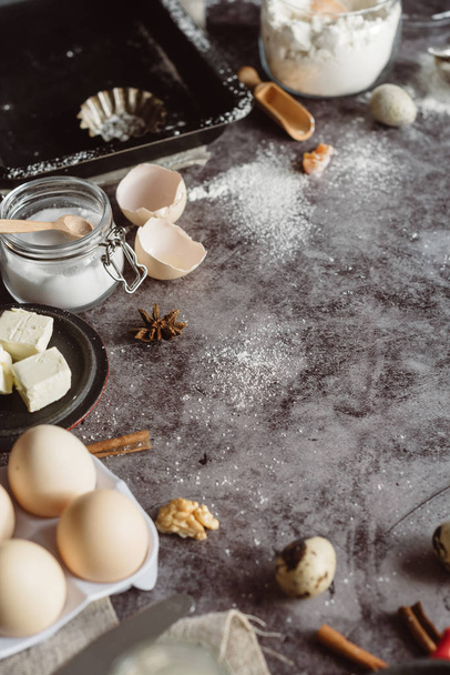 Healthy baking ingredients. Spoon with flour, dishes, eggs, butter salt and rolling pin on a grey background.Bakery background frame. Top view, copy space. - Valokuva, kuva