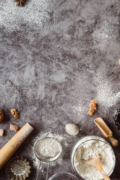 Healthy baking ingredients. Spoon with flour, dishes, eggs, butter salt and rolling pin on a grey background.Bakery background frame. Top view, copy space. - Foto, afbeelding