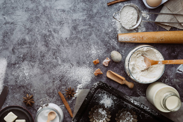Healthy baking ingredients. Spoon with flour, dishes, eggs, butter salt and rolling pin on a grey background.Bakery background frame. Top view, copy space. - Фото, изображение