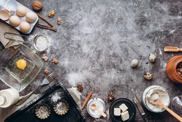 Healthy baking ingredients. Spoon with flour, dishes, eggs, butter salt and rolling pin on a grey background.Bakery background frame. Top view, copy space. - Foto, Imagen