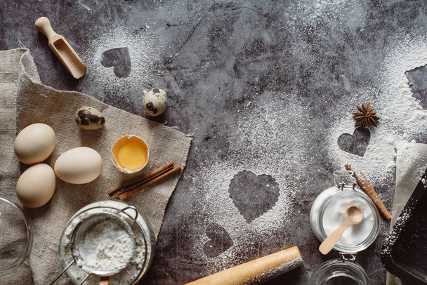 Healthy baking ingredients. Background with flour, rolling pin, eggs, and heart shape on kitchen gray kitchen table.  Top view for Valentines day cooking. Copy space. - Photo, Image