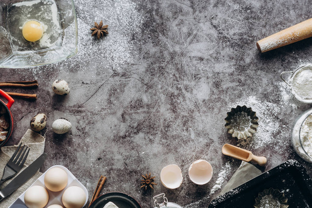 Healthy baking ingredients. Spoon with flour, dishes, eggs, butter salt and rolling pin on a grey background.Bakery background frame. Top view, copy space. - 写真・画像
