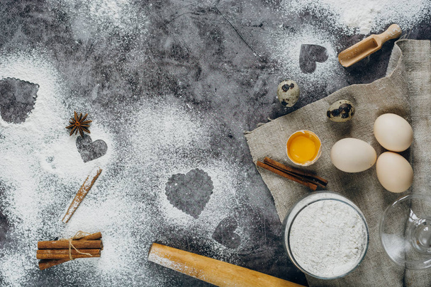 Healthy baking ingredients. Background with flour, rolling pin, eggs, and heart shape on kitchen gray kitchen table.  Top view for Valentines day cooking. Copy space. - 写真・画像