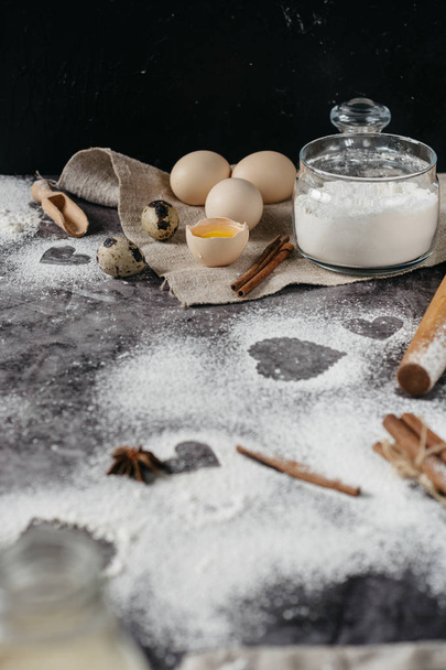 Healthy baking ingredients. Background with flour, rolling pin, eggs, and heart shape on kitchen gray kitchen table.  Top view for Valentines day cooking. Copy space. - Foto, Bild