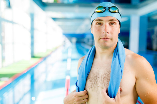 Photo of young swimmer with towel around neck standing in pool during workout - Фото, зображення