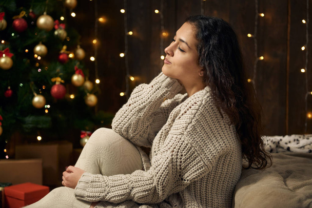 Noel ışıkları ve dekorasyon, beyaz, koyu ahşap arka plan, kış tatil kavramı üzerinde köknar ağacı giymiş genç kızdır - Fotoğraf, Görsel