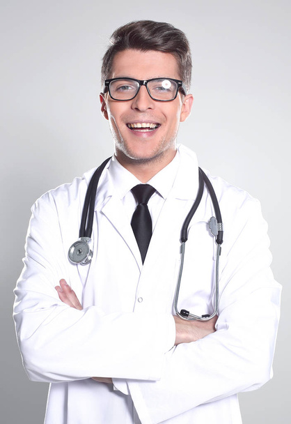 Handsome doctor is looking at camera while standing with folded  - Фото, изображение