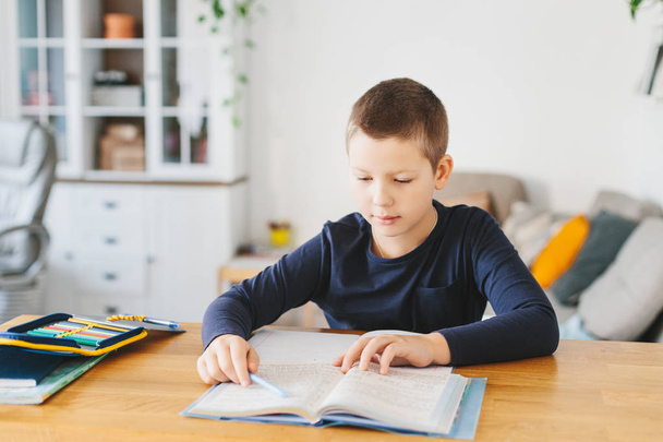 Schoolboy doing his homework on desk at home. Homeschooling concept - Foto, afbeelding