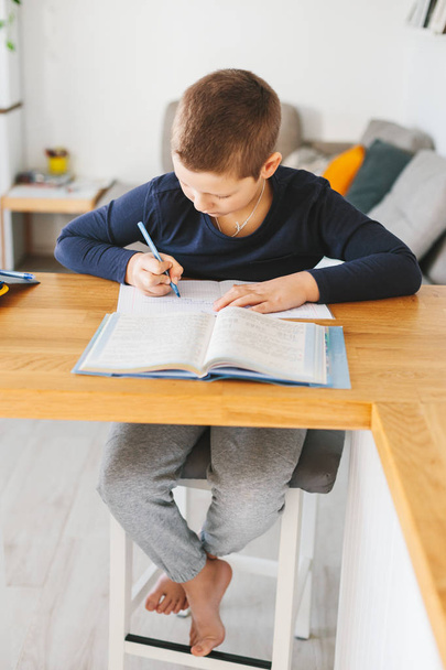 Schoolboy doing his homework on desk at home. Homeschooling concept - Zdjęcie, obraz
