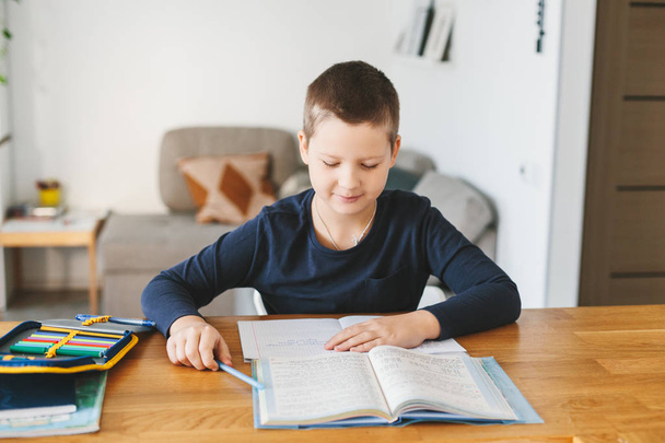 Schoolboy doing his homework on desk at home. Homeschooling concept - Photo, Image