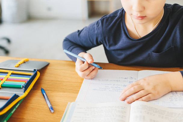 自宅の机の上のウクライナ語の言語の彼の数学の宿題をしている少年。ホーム スクーリングのコンセプト - 写真・画像