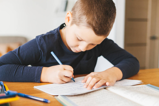 Schoolboy doing his maths homework in ukrainian language on desk at home. Homeschooling concept - Foto, Imagem