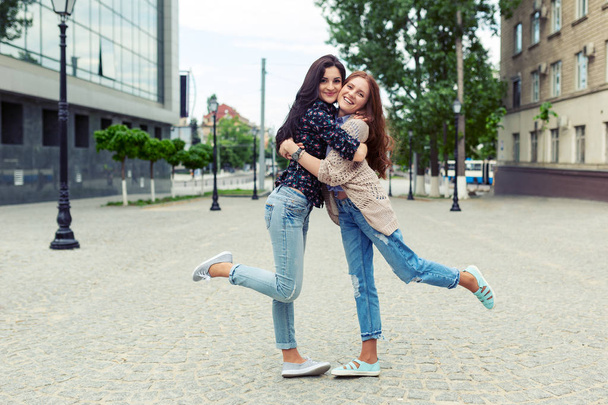 Porträt sorglos lächelnder Schwestern, die sich umarmen und gemeinsam Spaß haben. Outdoor-Foto von schönen kaukasischen jungen Damen verbringen Wochenende zusammen. - Foto, Bild