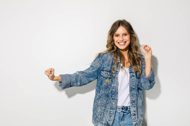 young attractive fashion model in jeans clothes posing on white background, smiling happy woman  - Fotó, kép