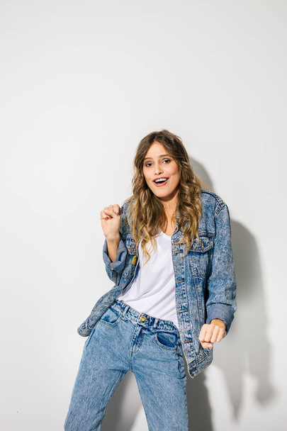 young attractive fashion model in jeans clothes posing on white background, smiling happy woman  - 写真・画像