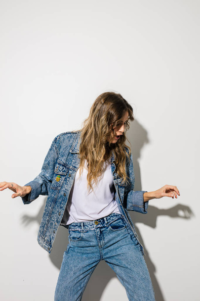 young happy woman dancing, smiling and being joyful in jeans outfit, on white background - Photo, Image