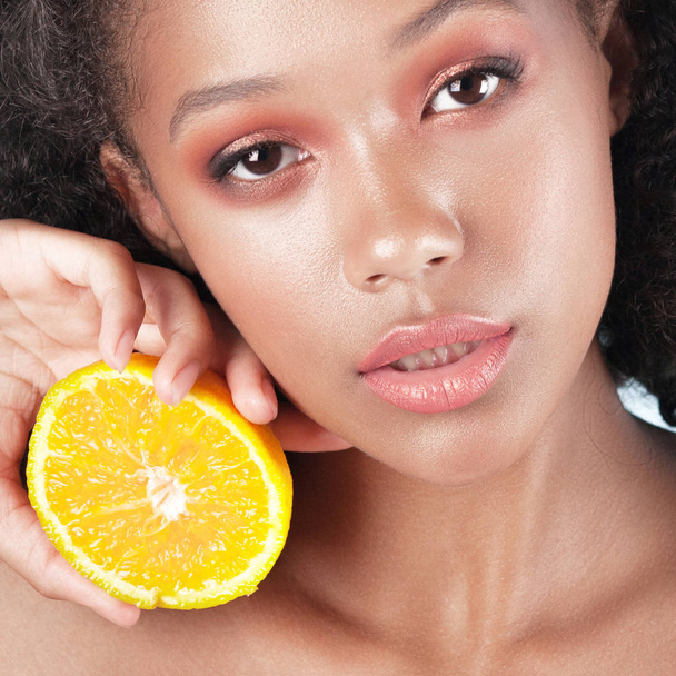 Young beautiful black girl with clean perfect skin with lemon close-up. Beauty portrait - Фото, зображення