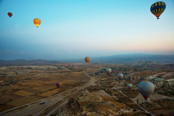 Cappadocia, Turkey: Hot air balloon flying over spectacular Cappadocia under the sky. Cappadocia at sunrise - landscape with hot air balloons flying over mountain valley in sunlight and mist. - Foto, immagini
